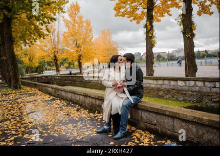 Una donna incinta siede in braccio al marito e tiene in mano dei piccoli calzini Foto Stock