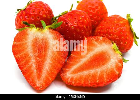 Vista ravvicinata di una fragola matura tagliata a metà con altre fragole sullo sfondo. su uno sfondo bianco semplice. Concetto di alimentazione sana. Foto Stock