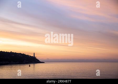 Guardando a est sul faro di Phare du Cap Ferrat e sul cielo colorato all'alba; Foto Stock