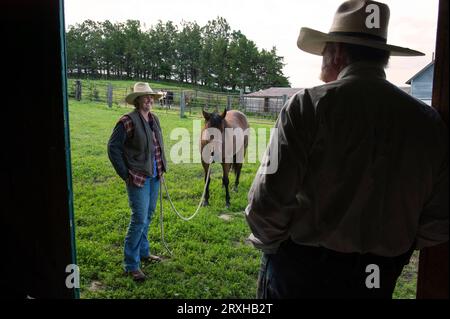 Cowboy e cowgirl stanno parlando in un ranch; Burwell, Nebraska, Stati Uniti d'America Foto Stock
