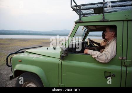 Due uomini guidano attraverso l'area di Mweya in Uganda, Africa, nel Queen Elizabeth National Park; Mweya, Uganda Foto Stock