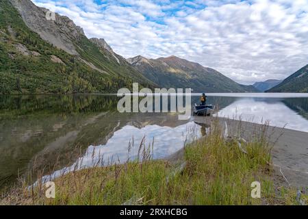 La donna si trova in canoa sulla riva del mare, affacciata sul remoto lago di Yukon, Canada Foto Stock