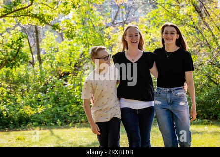 La madre trascorre del tempo di qualità all'aperto con i suoi figli adolescenti, passeggiando insieme in un parco cittadino durante un caldo pomeriggio autunnale; Leduc, Alberta, Canada Foto Stock