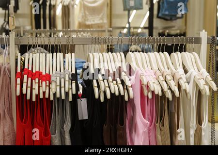 T-shirt o abiti da donna sono appesi a appendiabiti in un negozio di abbigliamento. Primo piano, sfondo. Foto Stock