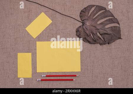 Alcuni fogli di carta gialla insieme ad alcune matite affilate con le gomme alle estremità e un foglio di carta asciutto e piatto Foto Stock
