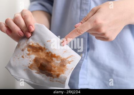 Donna che mostra macchie di caffè sulla giacca su sfondo sfocato, primo piano Foto Stock