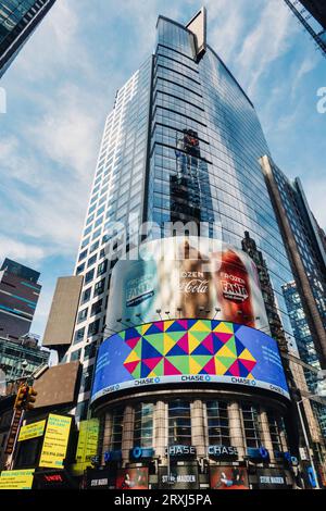 Enormi cartelloni pubblicitari elettronici, illuminano un grattacielo all'angolo tra la 42nd St. E la settima Avenue a Times Square, 2023, New York City, USA Foto Stock