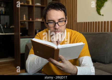Giovane seduto in una caffetteria, leggendo un libro e godendosi il tempo libero Foto Stock
