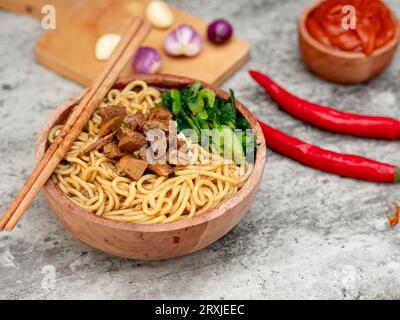 Spaghetti di pollo indonesiani chiamati mie ayam conditi con carne di pollo e senape verde serviti in una ciotola Foto Stock