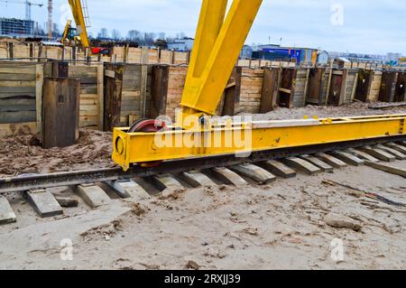 Grande ferro metallo giallo sostiene su rotaie con ruote con un motore a induzione di una grande costruzione stazionaria industriale potente gru a portale di A. Foto Stock