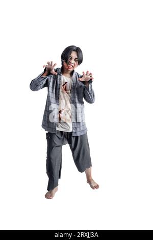 Uno zombie spaventoso con sangue e ferite sul suo corpo che cammina isolato su uno sfondo bianco Foto Stock