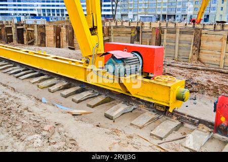 Grande ferro metallo giallo sostiene su rotaie con ruote con un motore a induzione di una grande costruzione stazionaria industriale potente gru a portale di A. Foto Stock