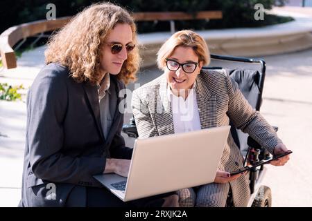 uomo d'affari e donna che lavorano all'aperto con un computer portatile Foto Stock