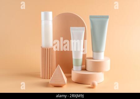 Bellissimi modelli cosmetici per annunci pubblicitari, tubi in plastica crema e bottiglie su sfondo beige chiaro con podi. Design di bellezza per prodotti di qualità superiore Foto Stock