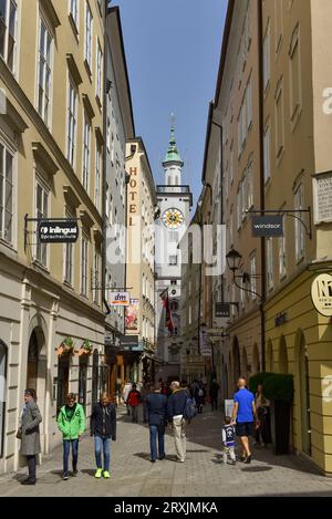 Vista della torre dell'orologio dell'Altes Rathaus (vecchio municipio), dei negozi e degli acquirenti su Sigmund-Haffner-Gasse, Salisburgo, Austria Foto Stock