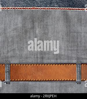 Fondo in denim grigio con cintura in pelle. Sfondo orizzontale o verticale con texture in tessuto jeans denim di colore grigio chiaro e cinturino in pelle marrone. MOC Foto Stock