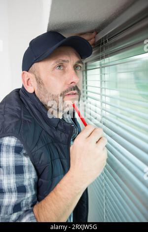 uomo che installa la serranda sul finestrino Foto Stock