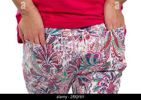 Un'immagine ravvicinata cattura le mani di una donna comodamente infilate nelle tasche posteriori dei suoi colorati pantaloni a fantasia Foto Stock