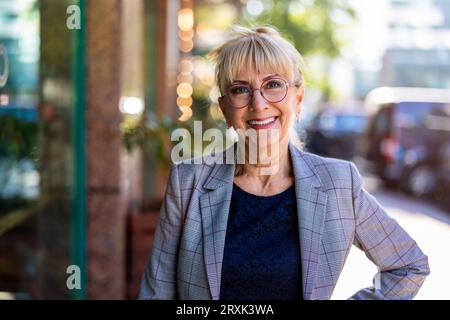 Ritratto di una donna d'affari anziana sorridente in città Foto Stock