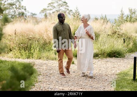 Felice coppia anziana che si tiene per mano e si diverte a camminare insieme all'aperto Foto Stock