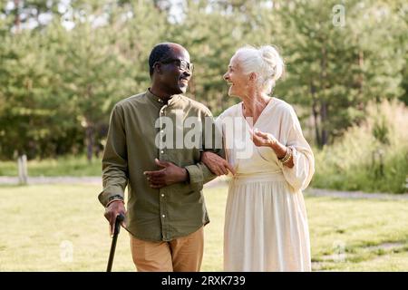 Coppia anziana felice che si diverte a passeggiare nel parco, parlano tra loro e ridono Foto Stock