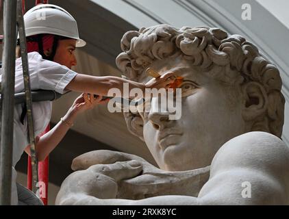 La restauratrice italiana Eleonora Pucci pulisce polvere e detriti dalla famosa statua in marmo del David di Michelangelo alla Galleria dell'Accademia di Firenze, Italia, il 25 settembre 2023. Il restauratore trascorre un giorno spolverando la statua di 5,17 metri. Il processo ha luogo ogni due mesi. Utilizza una serie di spazzole morbide e un aspirapolvere a bassa pressione per rimuovere delicatamente la polvere e i depositi di sporcizia che inevitabilmente si verificano quando ci sono così tanti visitatori che si affollano per vedere i capolavori. La statua è stata realizzata dal maestro italiano tra il 1501-1504 da un blocco di marmo. Rappresenta il Bi Foto Stock