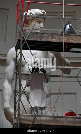 La restauratrice italiana Eleonora Pucci pulisce polvere e detriti dalla famosa statua in marmo del David di Michelangelo alla Galleria dell'Accademia di Firenze, Italia, il 25 settembre 2023. Il restauratore trascorre un giorno spolverando la statua di 5,17 metri. Il processo ha luogo ogni due mesi. Utilizza una serie di spazzole morbide e un aspirapolvere a bassa pressione per rimuovere delicatamente la polvere e i depositi di sporcizia che inevitabilmente si verificano quando ci sono così tanti visitatori che si affollano per vedere i capolavori. La statua è stata realizzata dal maestro italiano tra il 1501-1504 da un blocco di marmo. Rappresenta il Bi Foto Stock