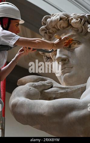 La restauratrice italiana Eleonora Pucci pulisce polvere e detriti dalla famosa statua in marmo del David di Michelangelo alla Galleria dell'Accademia di Firenze, Italia, il 25 settembre 2023. Il restauratore trascorre un giorno spolverando la statua di 5,17 metri. Il processo ha luogo ogni due mesi. Utilizza una serie di spazzole morbide e un aspirapolvere a bassa pressione per rimuovere delicatamente la polvere e i depositi di sporcizia che inevitabilmente si verificano quando ci sono così tanti visitatori che si affollano per vedere i capolavori. La statua è stata realizzata dal maestro italiano tra il 1501-1504 da un blocco di marmo. Rappresenta il Bi Foto Stock