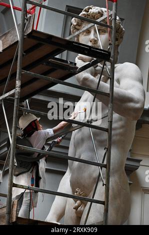 La restauratrice italiana Eleonora Pucci pulisce polvere e detriti dalla famosa statua in marmo del David di Michelangelo alla Galleria dell'Accademia di Firenze, Italia, il 25 settembre 2023. Il restauratore trascorre un giorno spolverando la statua di 5,17 metri. Il processo ha luogo ogni due mesi. Utilizza una serie di spazzole morbide e un aspirapolvere a bassa pressione per rimuovere delicatamente la polvere e i depositi di sporcizia che inevitabilmente si verificano quando ci sono così tanti visitatori che si affollano per vedere i capolavori. La statua è stata realizzata dal maestro italiano tra il 1501-1504 da un blocco di marmo. Rappresenta il Bi Foto Stock