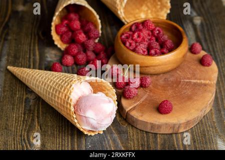 Cono di waffle con gelato al gelato bianco rosa e lamponi, sapore di lampone di gelato in un cono di waffle Foto Stock