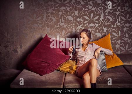 Giovane donna seduta sul divano in discoteca Foto Stock
