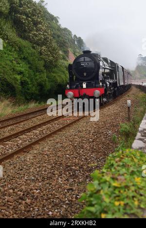 In un giorno coperto, la classe Royal Scot della LMS No 46115 Scots Guardsman corre lungo la diga di Teignmouth con il tour ferroviario del Royal Duchy. Foto Stock