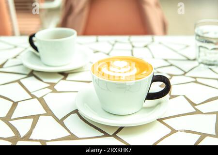 Tazza di cappuccino con schiuma sul tavolo nel bar. Foto Stock