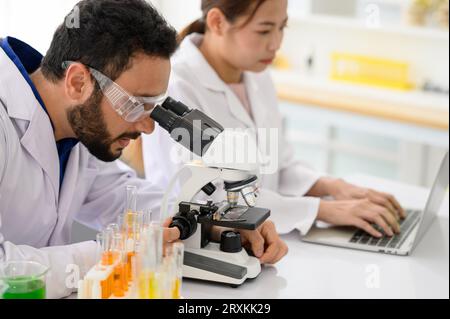 Ricercatore di biotecnologie microbiologo con microscopio in laboratorio Foto Stock