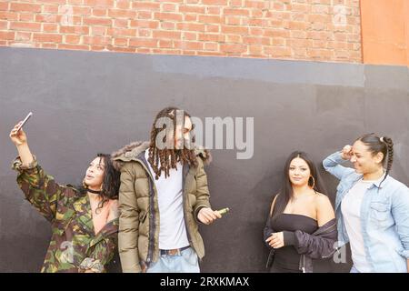 Giovane donna prendendo selfie con gli amici Foto Stock