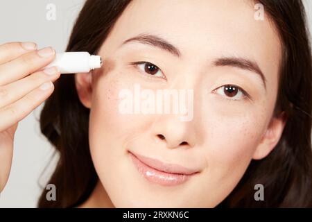 Giovane donna l'applicazione di crema per il viso dal tubo Foto Stock