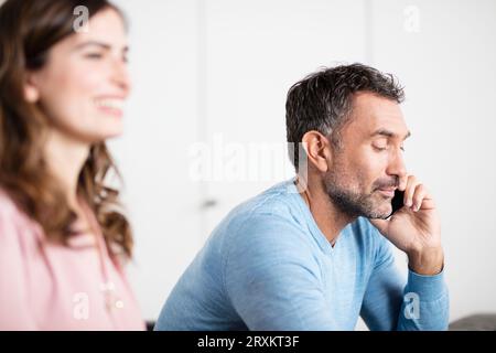 Imprenditore maturo parlando sullo smartphone in office Foto Stock