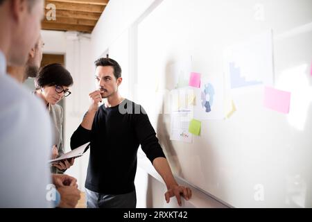 Gli imprenditori in discussione dalla lavagna in office Foto Stock