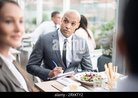 Imprenditore iscritto su appunti durante il ristorante meeting Foto Stock