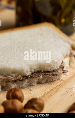 fette di pane con burro al cioccolato sul tavolo, cucinando un semplice dolce fatto in casa utilizzando burro al cioccolato con pane bianco Foto Stock