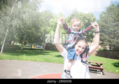 Bambini sulle spalle che godono di una giornata di sole nel parco Foto Stock