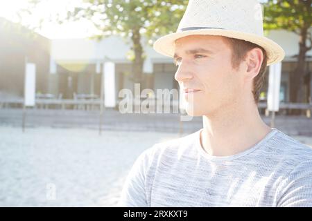 Giovane uomo che indossa la paglia trilby hat sulla spiaggia Foto Stock