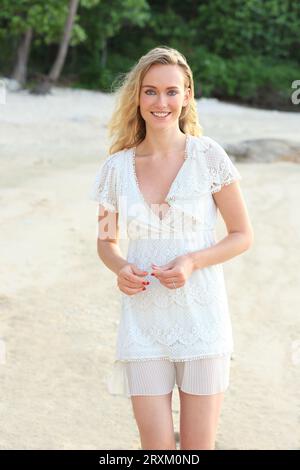Giovane donna indossa abito bianco sulla spiaggia Foto Stock