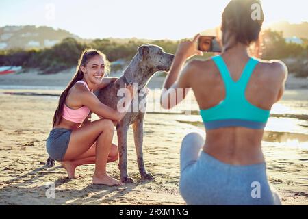 Giovane donna petting cane mentre il suo amico prende fotografia Foto Stock