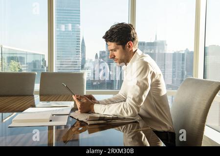 Giovane uomo utilizzando tablet PC al tavolo in New York City Foto Stock
