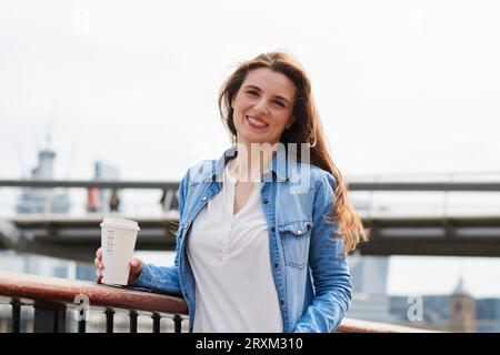 Sorridente metà donna adulta azienda caffè Foto Stock