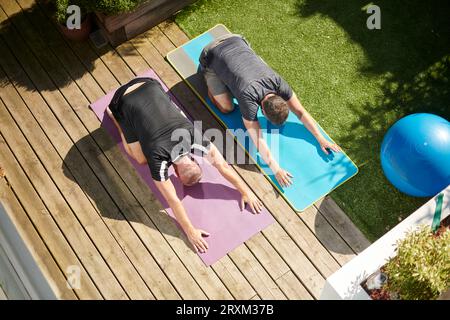 Coppia matura che pratica yoga nel cortile sul retro Foto Stock