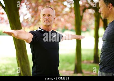 Uomini maturi che praticano yoga nel parco Foto Stock