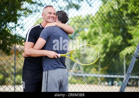 Coppia matura che abbraccia il campo da tennis Foto Stock