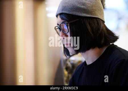 Giovane uomo che indossa berretto e occhiali Foto Stock